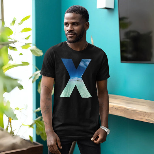 A man in a black t-shirt with a large graphic letter 'X' with an ocean wave design inside the letter. The man is standing against a vibrant teal background, casually posing with his hands partially in his pockets, showcasing a relaxed demeanor. He has a short haircut, a light beard, and wears a confident, pleasant expression.