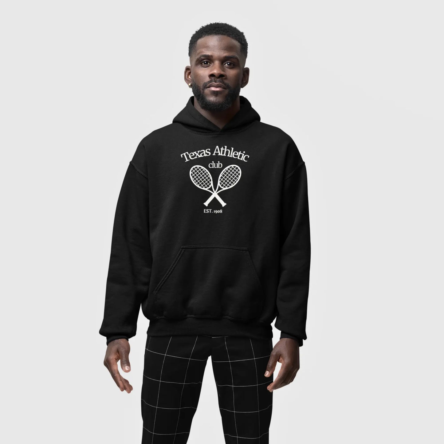 Man in a black hoodie with 'Texas Athletic Club EST. 1985' and crossed tennis rackets graphic on the front.