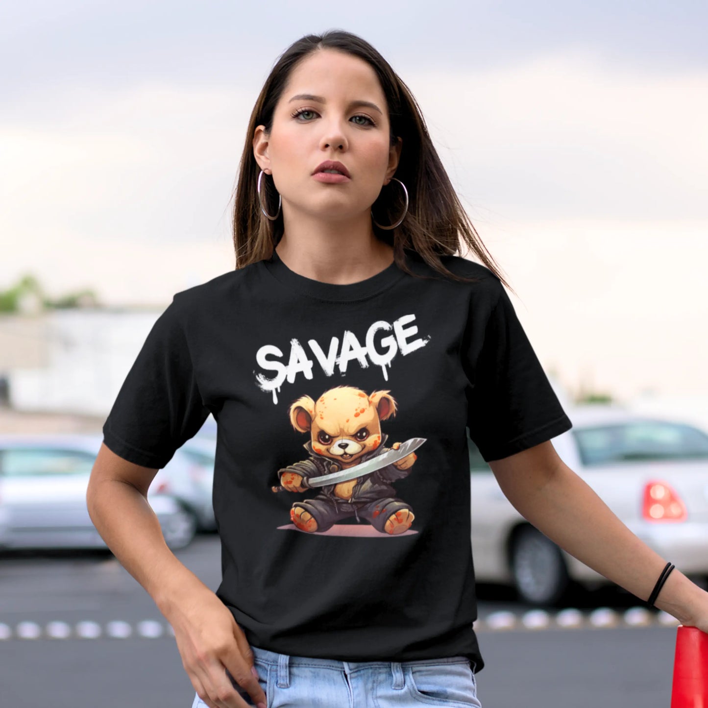 A woman with a focused gaze, wearing a black t-shirt featuring the word 'SAVAGE' above a graphic of an animated bear character wielding a sword.