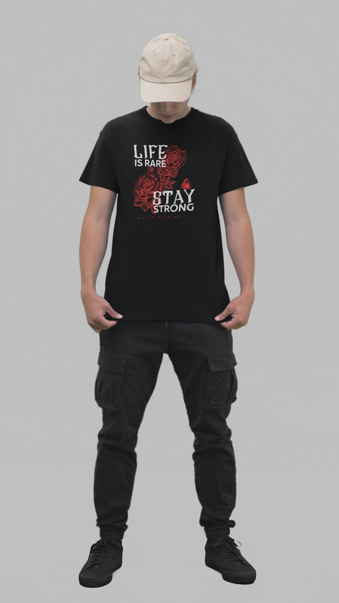 A young man models confidently, wearing a black t-shirt that features a red rose design and an empowering message in white text reading 'LIFE IS RARE STAY STRONG' with 'Never Give Up'