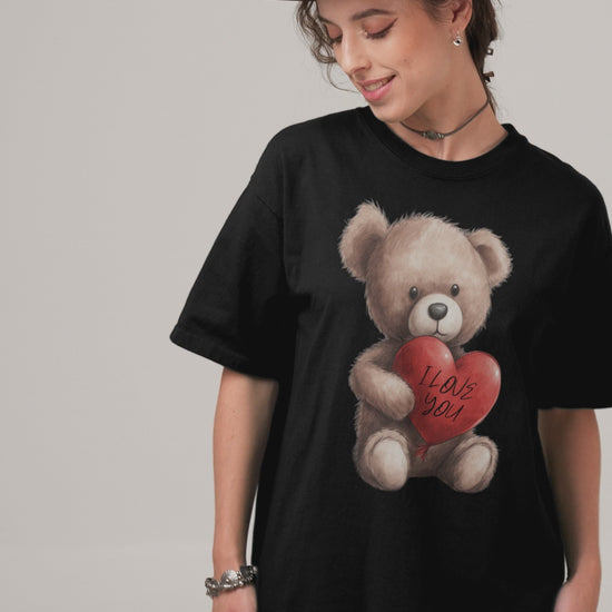 A woman wearing a black oversized t-shirt with a graphic of a cuddly teddy bear holding a red heart that says 'I Love You', paired with a delicate lace skirt and layered bracelets, creating a blend of soft and edgy styles.
