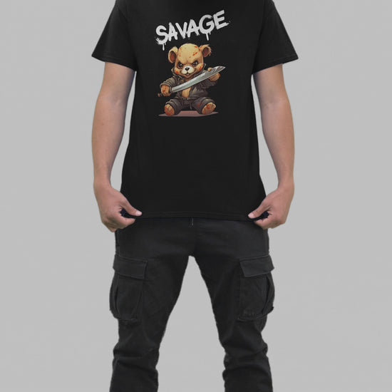 A young man in a black t-shirt featuring the word 'SAVAGE' in white dripping letters, with a graphic of a battle-ready teddy bear below.